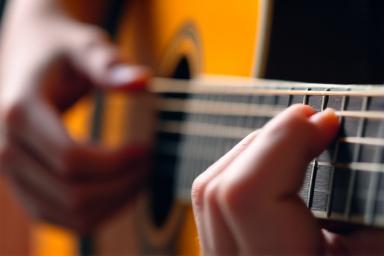 Gros plan sur la main d'un étudiant jouant de la guitare acoustique